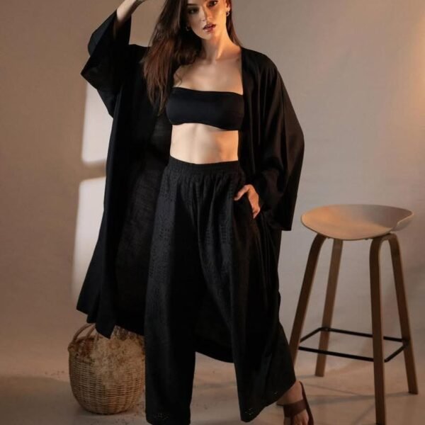 Black three-piece outfit with a relaxed open layer, bandeau-style top and high-waisted bottoms.