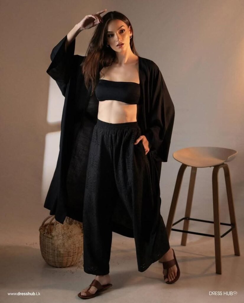 Black three-piece outfit with a relaxed open layer, bandeau-style top and high-waisted bottoms.