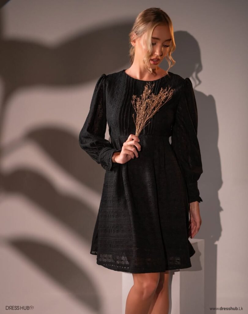Black short dress with a round neckline, long sleeves and a geometric patterned texture.