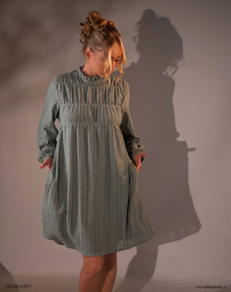 Sage-toned short dress with a high neckline, long sleeves and a geometric patterned texture.