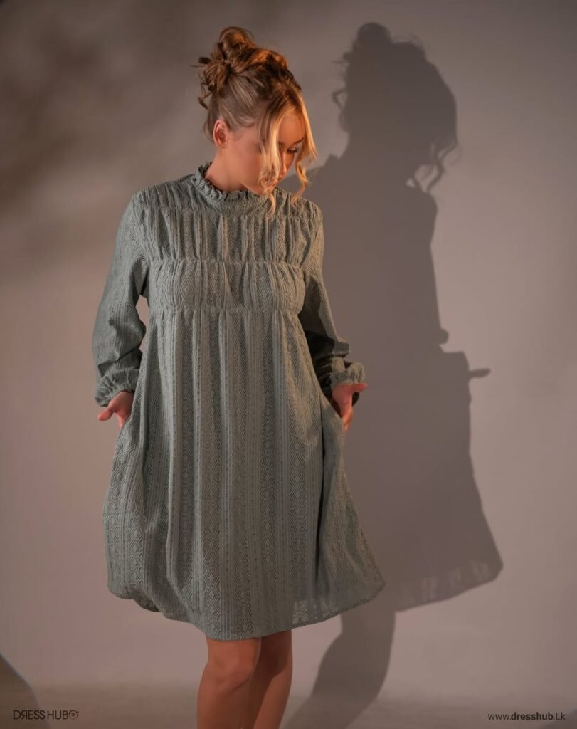 Sage-toned short dress with a high neckline, long sleeves and a geometric patterned texture.